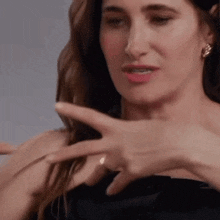 a woman in a black dress is pointing at herself with her fingers .