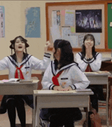 a group of girls are sitting at desks in a classroom laughing .