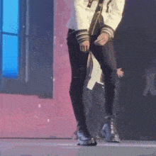 a man in a white jacket and black pants is standing on a stage .