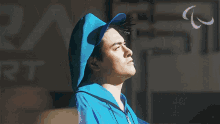 a man wearing a blue hoodie and a blue hat looks up at the sky