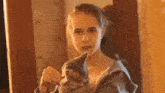 a young girl is holding a cat in her arms and looking at it in a mirror .