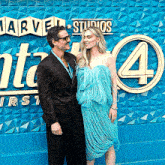 a man and a woman pose in front of a sign that says marvel studios