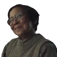 a woman wearing glasses and a sweater smiles for the camera