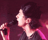 a man singing into a microphone wearing a pink hat