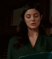 a woman in a green shirt is holding a clipboard in her hand and making a funny face .