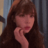 a close up of a woman 's face with her hand on her face .