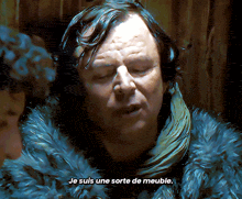 a man wearing a fur coat and scarf says je suis une sorte de meuble