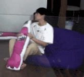 a man is sitting on a couch holding a pillow that looks like a pringles