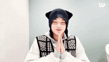 a man wearing a cat ear hat is praying with his hands together