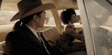 a man in a cowboy hat sits next to a woman in a suit and tie