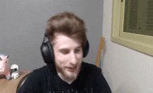 a man wearing headphones is sitting at a desk in front of a guitar .