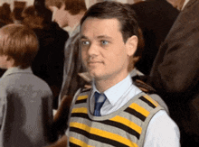 a man wearing a striped vest and tie stands in a crowd