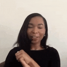 a woman is sitting in a chair with her eyes closed and holding her hands together .