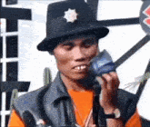 a man wearing a hat and vest is holding a microphone .