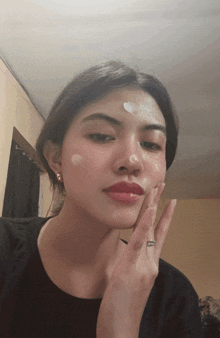 a woman with a ring on her finger is applying lotion to her face