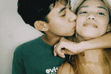 a man kisses a woman on the cheek while wearing a green shirt that says evi on it
