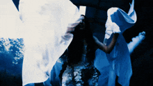 a woman in a white dress is waving a white cloth in the dark