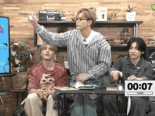 a group of young men sitting around a table with a timer that reads 0:07