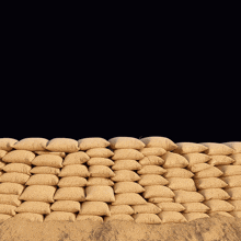 a man holding up a sign that says no behind a pile of sandbags