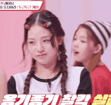 a girl with braids is standing next to another girl who is wearing a striped hat and a red shirt