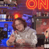 a man is pouring a glass of wine in front of a neon sign that says " on "