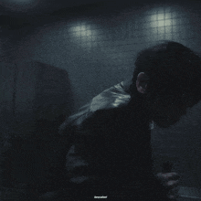 a man in a leather jacket is holding a bottle in a dark room with the words keycallast written below him