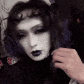 a woman with blue hair and white makeup has a vampire bite on her face