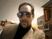 a man wearing sunglasses and a turtleneck looks at the camera .
