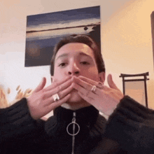 a man covering his mouth with his hands with a ring on his finger