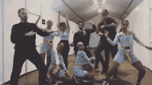 a group of people are dancing together in a room with a white tent in the background .