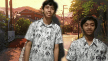 two boys are standing next to each other on a sidewalk wearing matching shirts