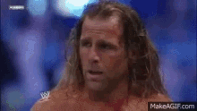 two men are wrestling in a ring with a crowd in the background .