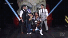 a group of men standing in front of a skull with the word nxt live on the bottom