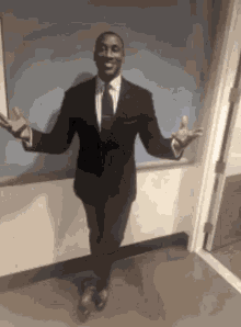 a man in a suit and tie is standing in a hallway with his arms outstretched .