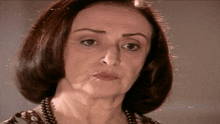 a close up of a woman 's face with a pearl necklace around her neck