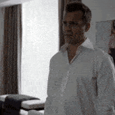 a man in a white shirt stands in a living room