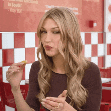 a woman is eating a chicken nugget in front of a sign that says " roy blk "
