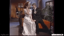 a bride and groom are sitting on a couch and looking at each other .