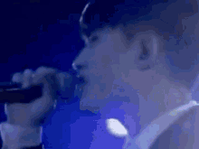 a man is singing into a microphone with a blue background