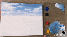 a painting of a cloudy sky is being painted on a canvas next to a palette