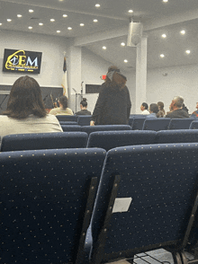 a group of people sitting in an auditorium with a sign above them that says cem