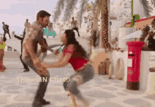 a man and a woman are dancing in front of a red post box .