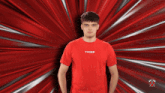 a man wearing a red tribe shirt stands in front of a red background
