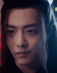 a close up of a man 's face with long hair looking at the camera