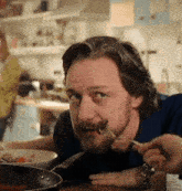 a man with a beard is eating a piece of food with a fork
