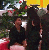 a man and a woman are sitting on a couch talking to each other in a room .