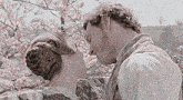 a man and woman are kissing in front of a cherry blossom tree .