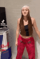 a woman is standing next to a can of red bull .
