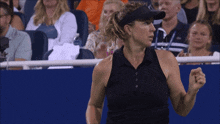 a woman wearing a black shirt and a black visor is standing in front of a crowd