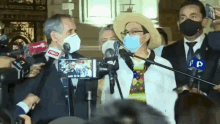 a group of people wearing face masks are standing in front of microphones with pd written on one of them